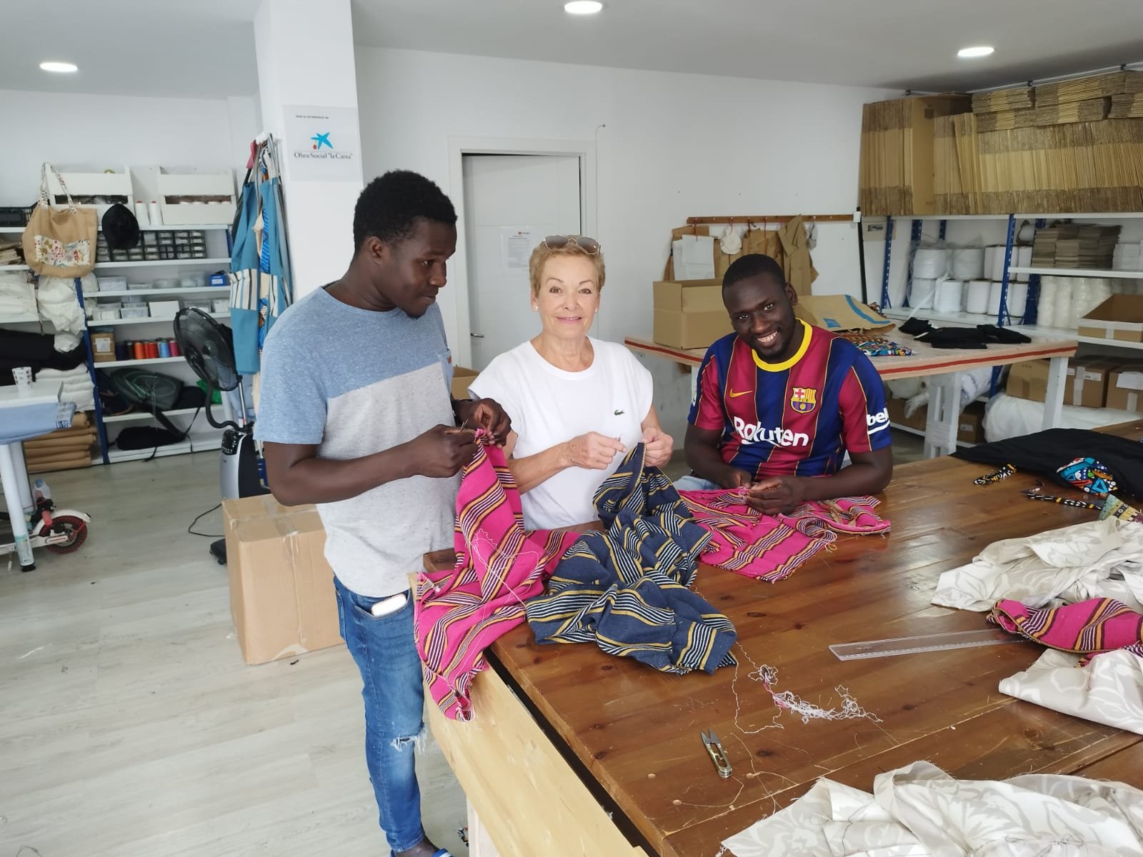 Personas participantes y voluntariado del Taller Textil Solidario del Centre Sant Martí trabajando juntas en la confección de prendas en el espacio de costura.