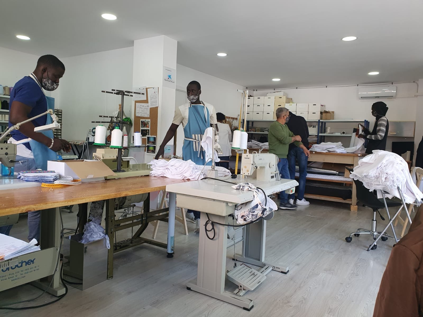 Actividad diaria en el Taller Textil Solidario del Centre Sant Martí, con personas participantes trabajando en máquinas de coser y en la preparación de prendas en un entorno formativo y laboral.