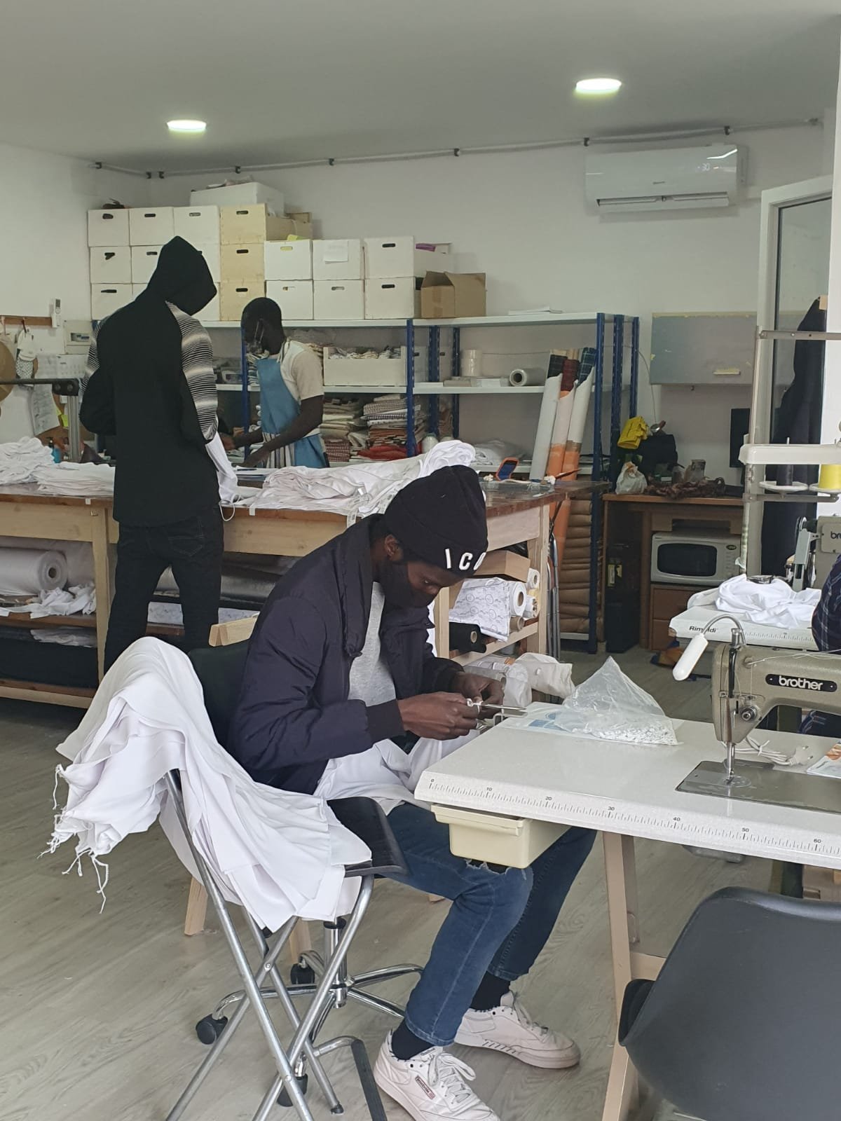 Persona trabajando en el Taller Textil Solidario del Centre Sant Martí, preparando prendas en un entorno formativo con maquinaria industrial.